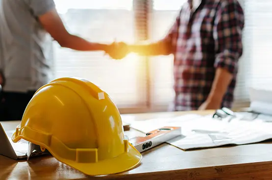 Peak Ten builders shaking hands over blueprints